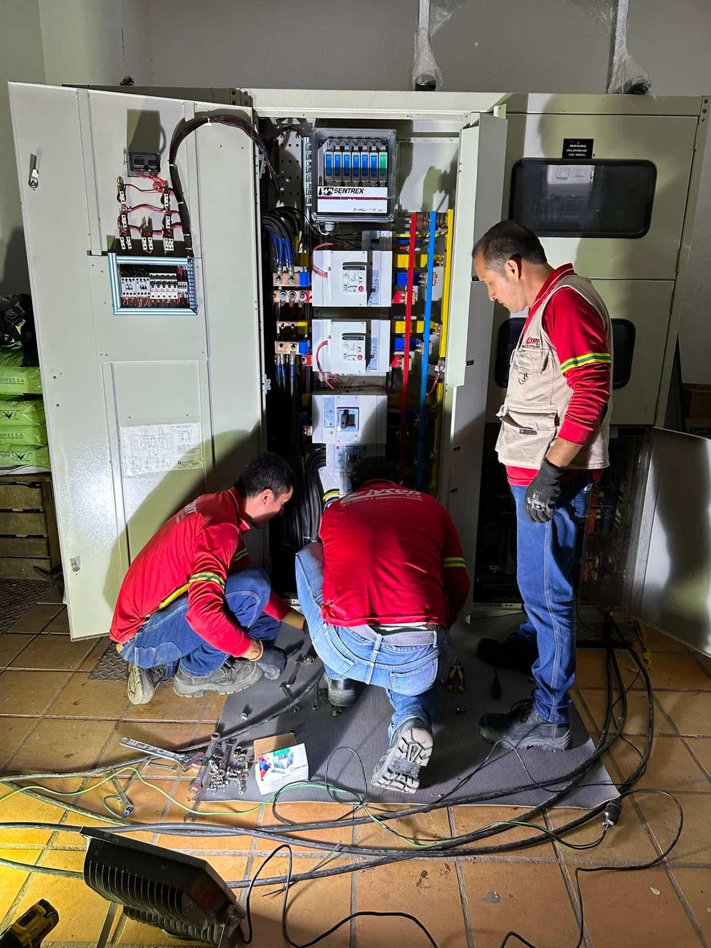 Tres técnicos trabajando en un tablero eléctrico